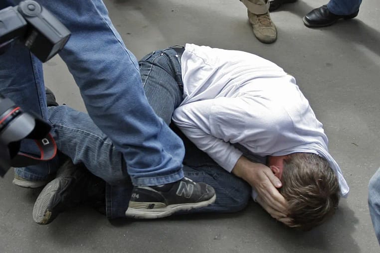 мальчик лежит на асфальте, закрыл лицо руками, одноклассник пинает его ногой