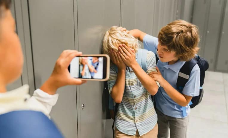 один мальчик бьет одноклассника, а другой снимает это на видео