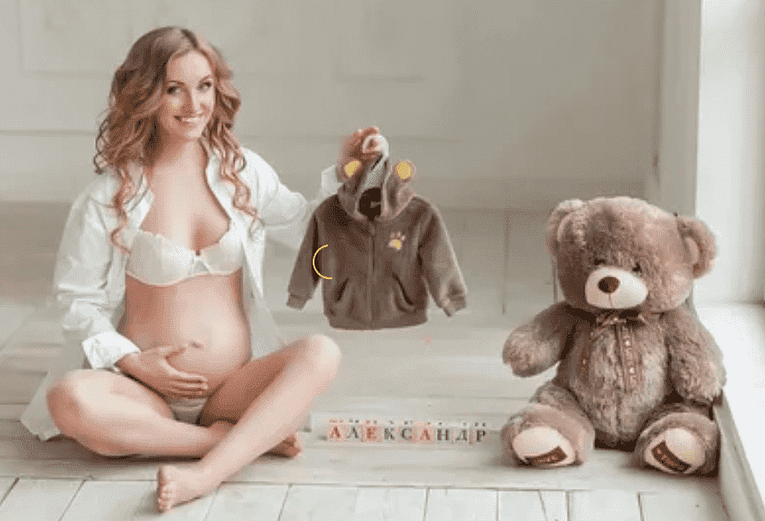 беременная с одеждой для новорожденного и медвежонком