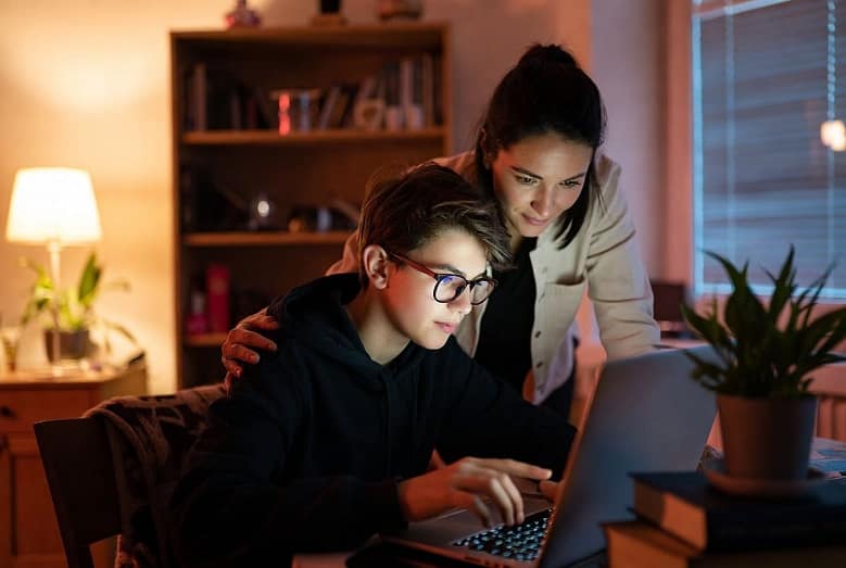 мать и сын-подросток смотрят на экран ноутбука