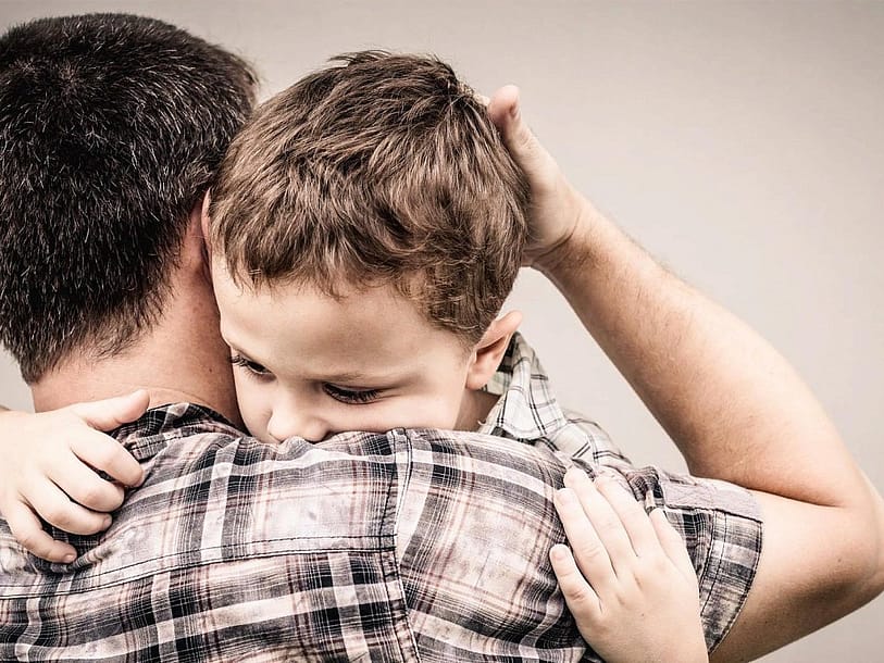 отец обнимает сына, жалеет его, гладит рукой по голове, сын обнимает отца за шею, положил голову ему на плечо