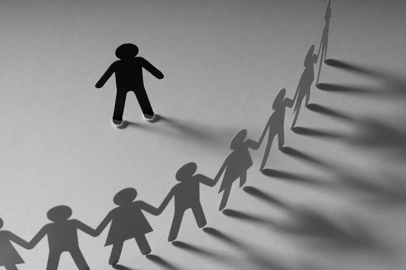 черная бумажная фигура человека окружена белыми фигурками, стоящими по кругу - символ буллинга