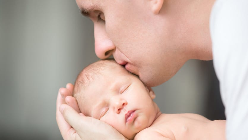 отец целует новорожденного